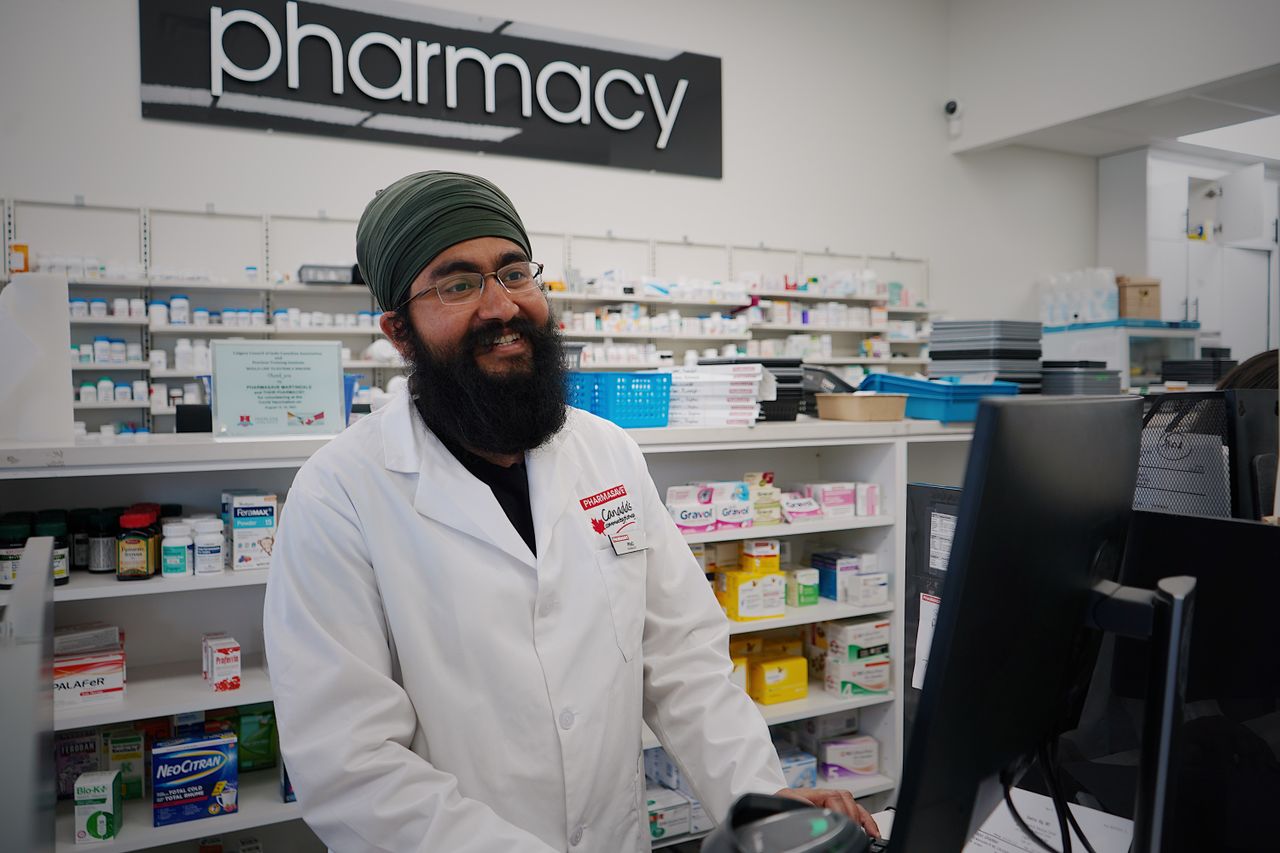 The Art of Drawing Readers In: Your attractive post title goes here Male pharmacist with a turban standing and smiling in a pharmacy, working at the counter.